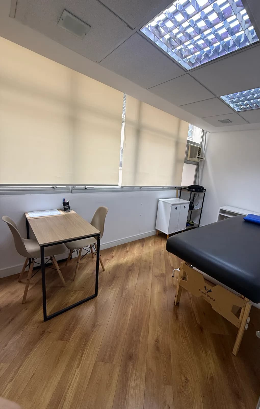 Sala de fisioterapia da unidade Consolação, com maca de atendimento, janelas com persianas e piso de madeira.