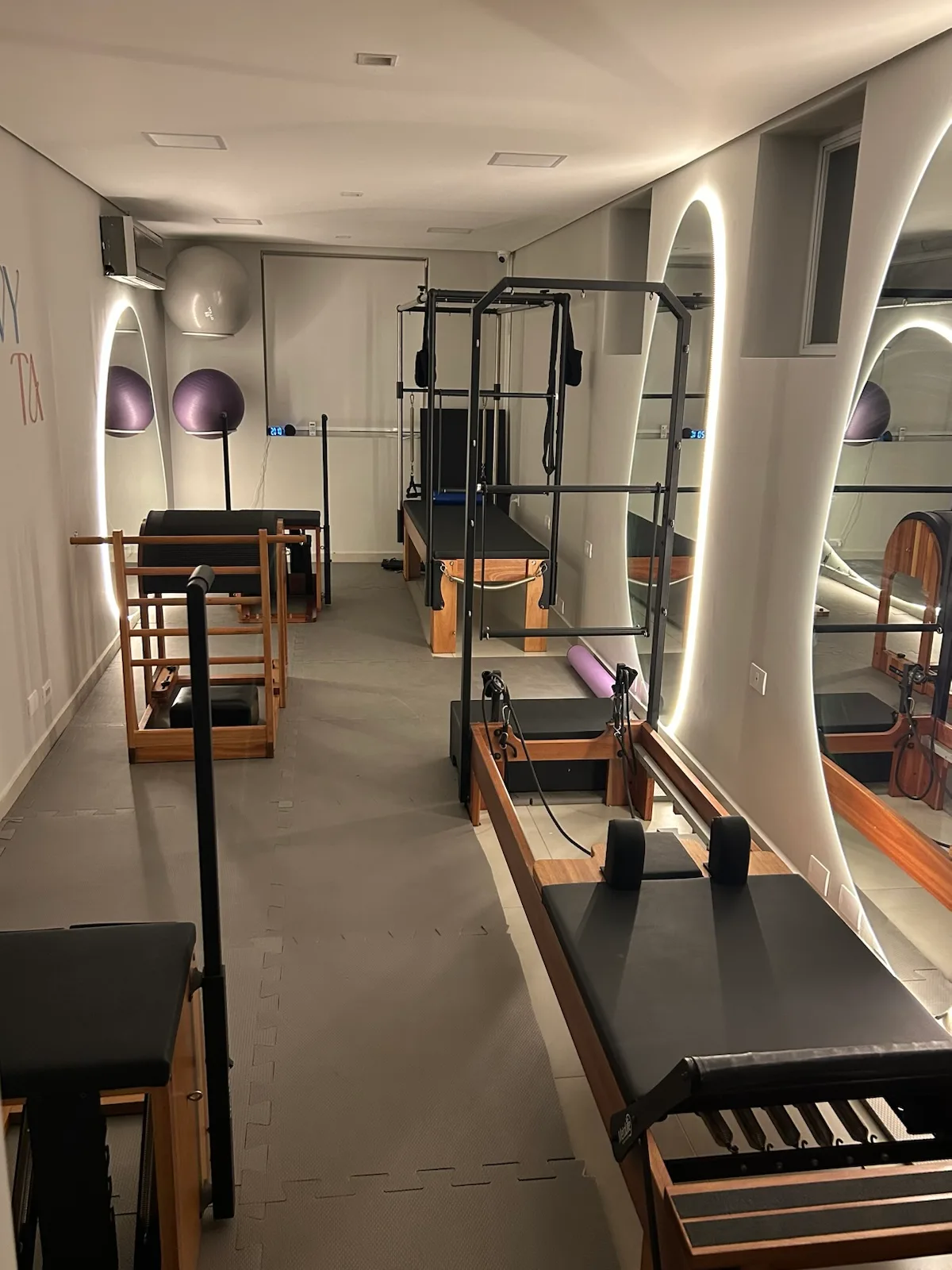 Corredor do estúdio de pilates da unidade Pinheiros com reformer, cadillac e escada.