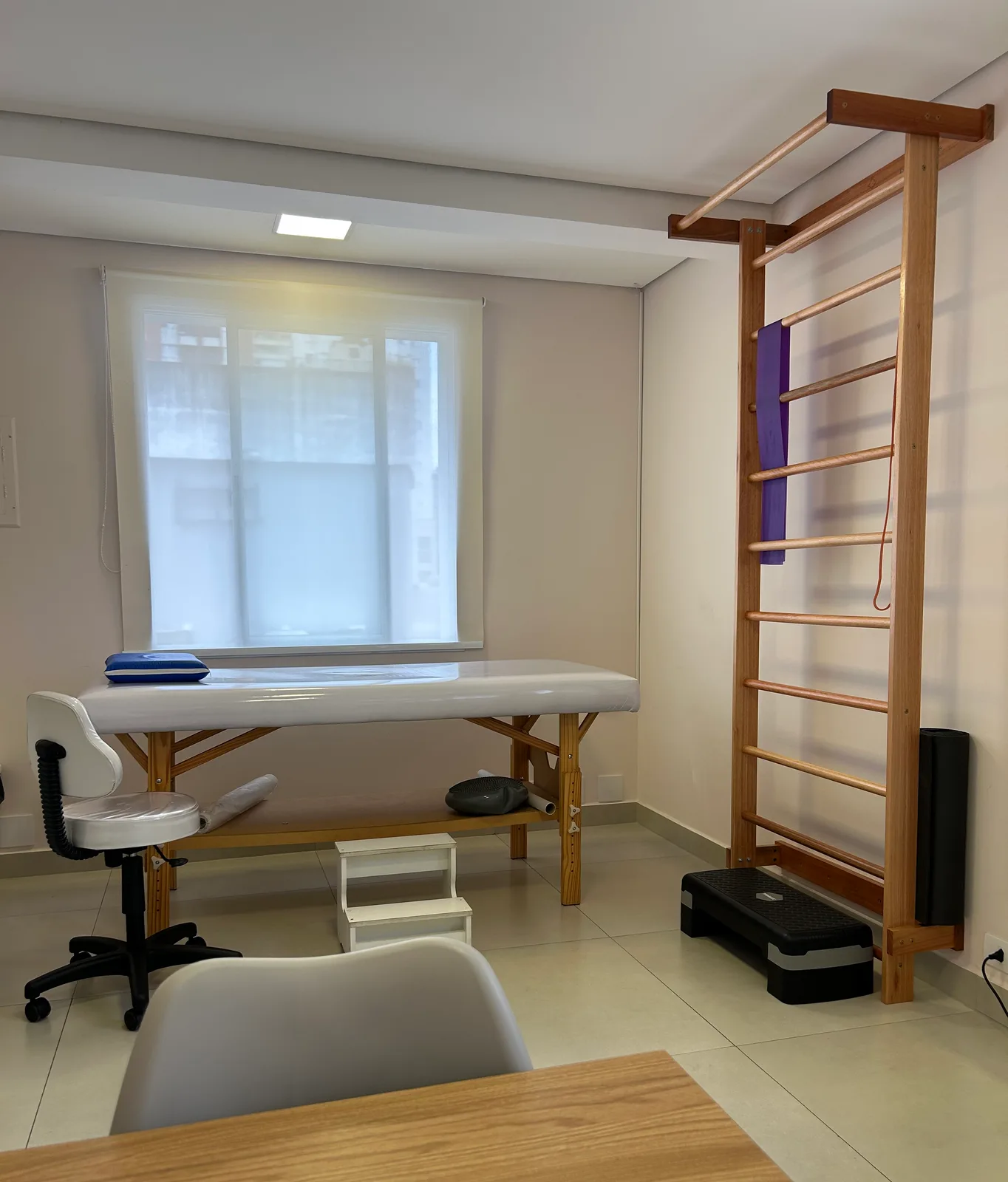 Sala de fisioterapia da unidade Pinheiros, com espaldar de madeira e maca de atendimento.