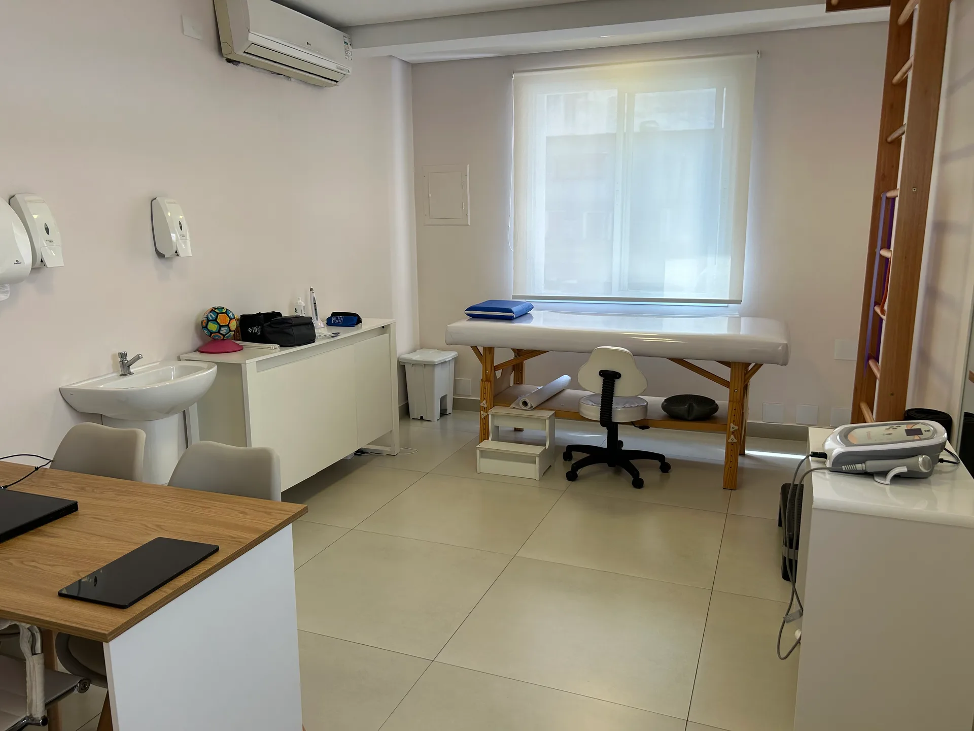 Sala de atendimento da unidade Pinheiros da Vyta, com maca de tratamento junto à janela e pia de higienização