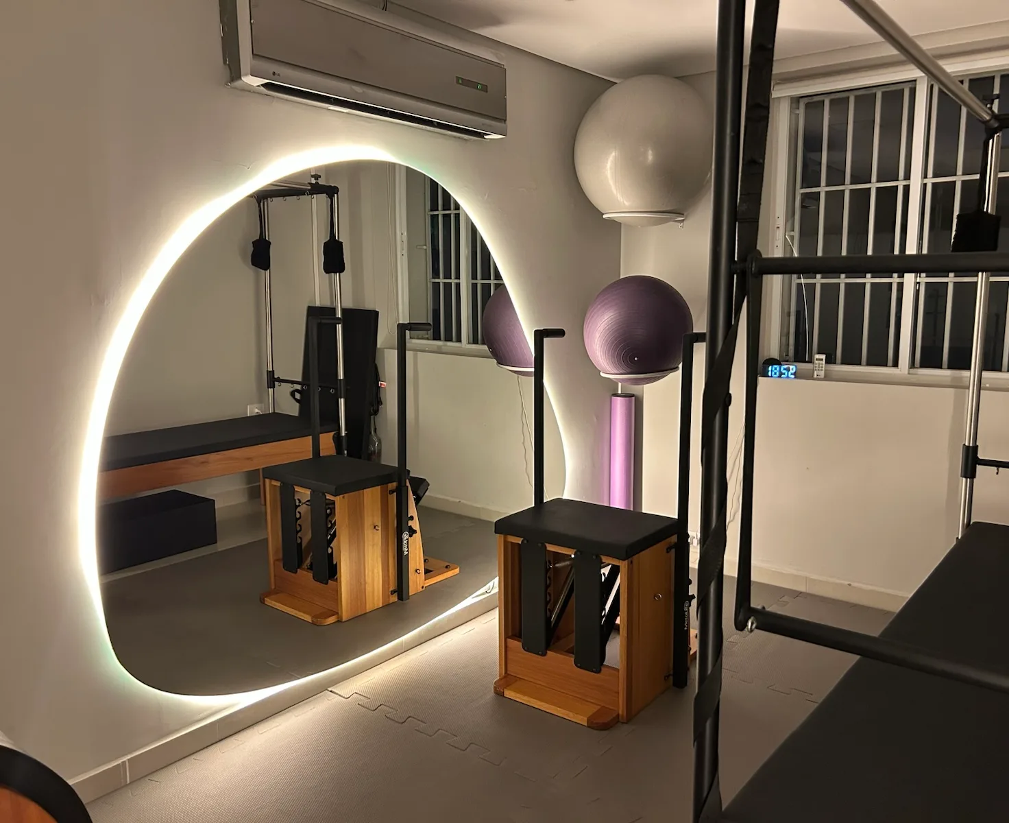 Cadeiras de pilates e bolas suíças refletidas no espelho do estúdio de Pinheiros.